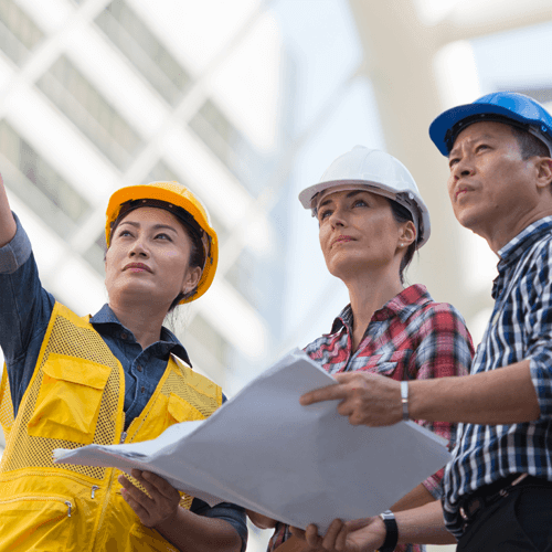 Two women and a man wearing hard hats at a construction site